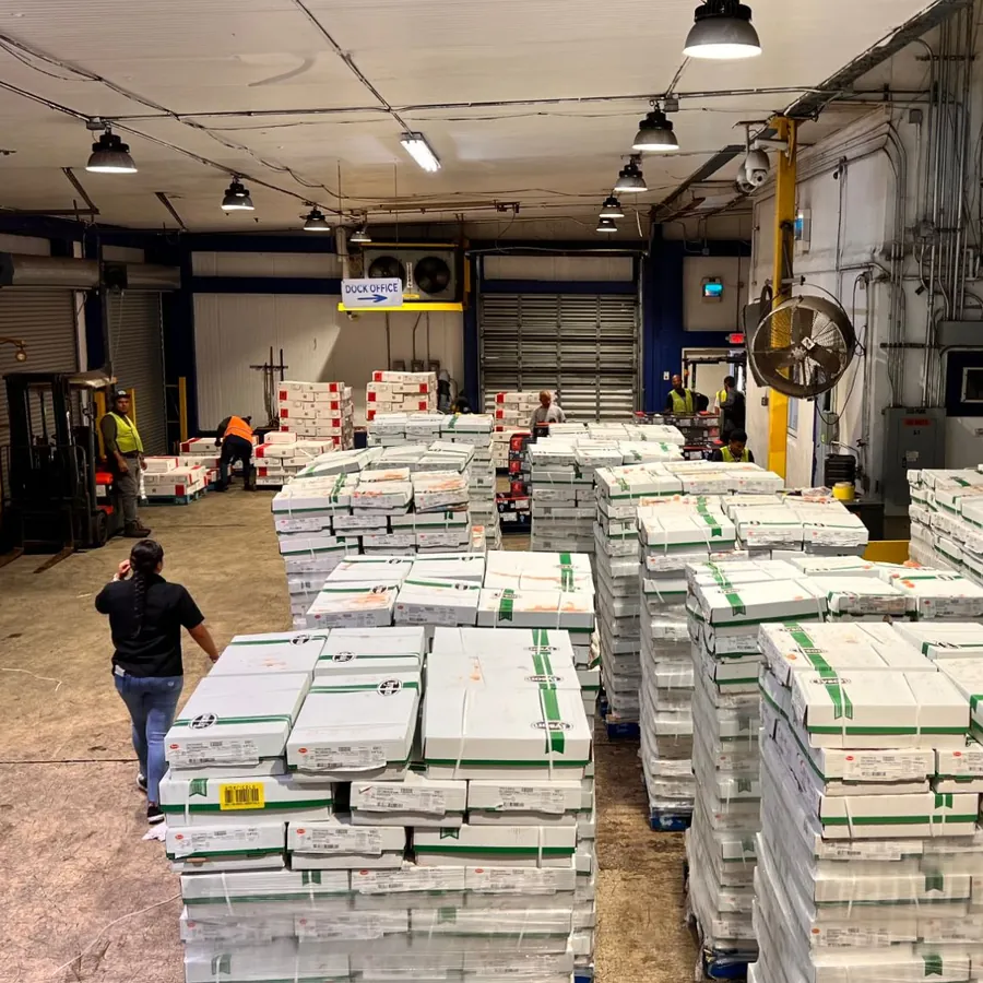 Team members and a forklift working among palletized cases near the dock office