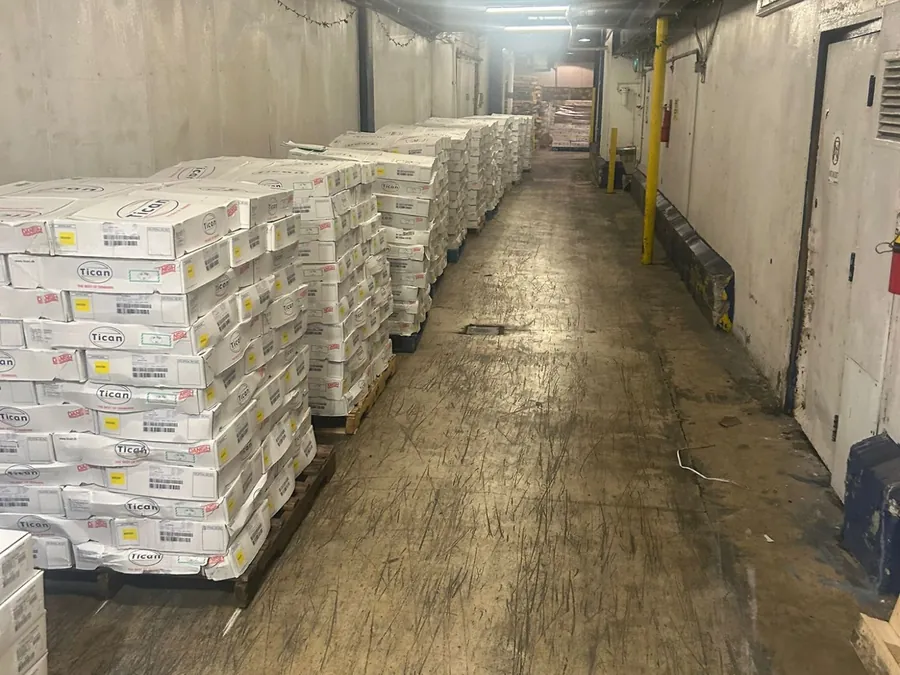 Long warehouse corridor lined with pallets of white cardboard cases