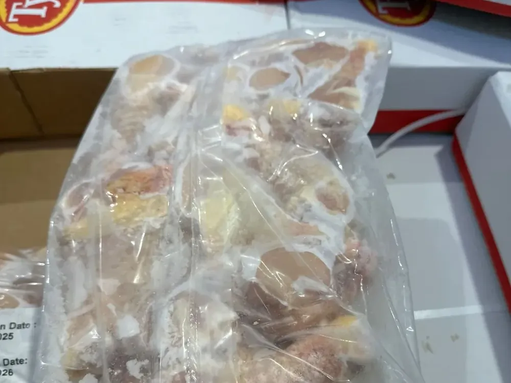 Sealed bag of frozen chicken pieces resting on stacked shipping cases